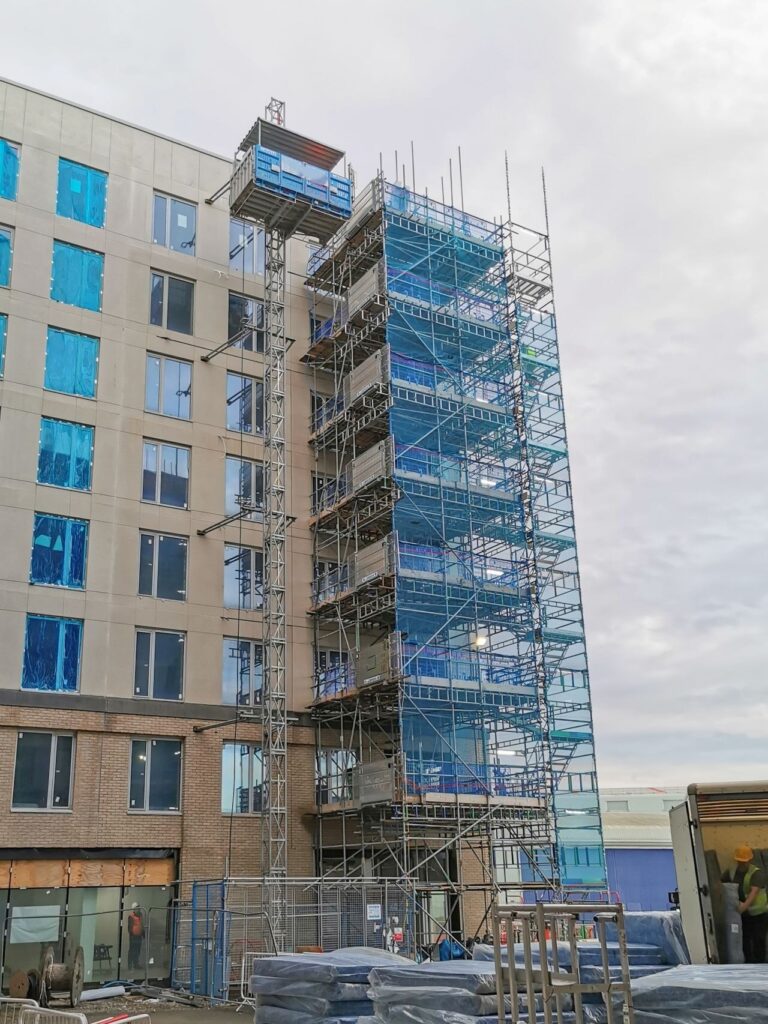Lift de chantier MABER en haut de son mât et tour escaliers d'échafaudage sur un immeuble en construction