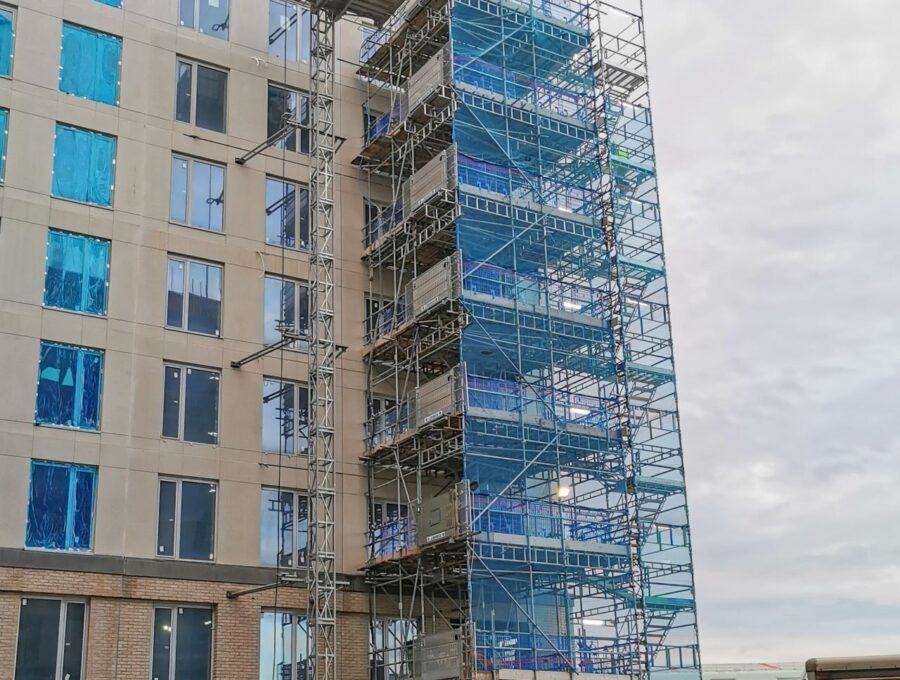 Lift de chantier MABER MBC 2000 en haut de son mât, à côté d'une tour escaliers sur un immeuble en construction