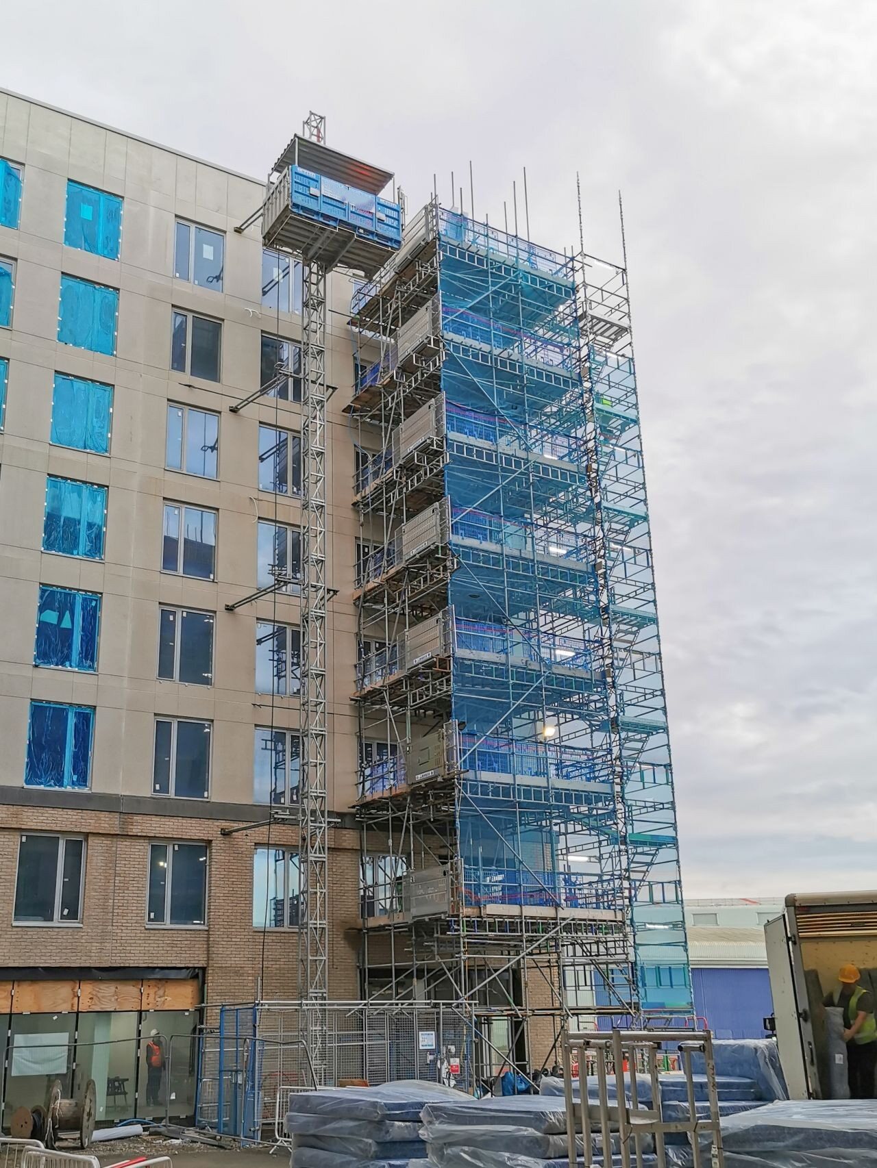 Lift de chantier MABER monté et réceptionné sur un immeuble, à côté d'une tour escaliers d'échafaudage