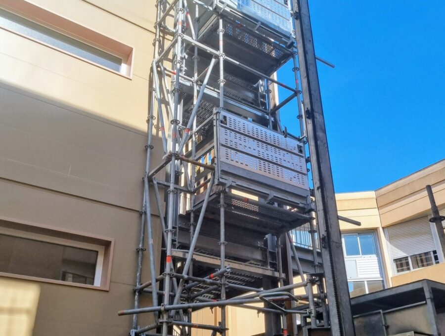 Lift de chantier MABER MBC 500 monté contre une tour escaliers d'échafaudage, palier à chaque niveau