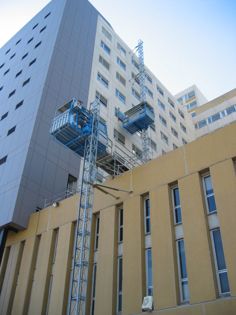 Deux lifts de chantier MABER montés sur la façade d'un immeuble, mâts ancrés étage par étage