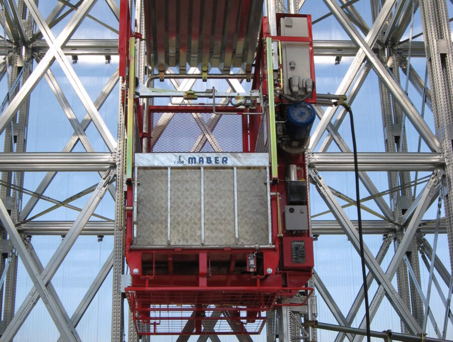 Cabine d'une plateforme de transport MABER sur son mât à crémaillère, avec son toit et sa porte rabattable
