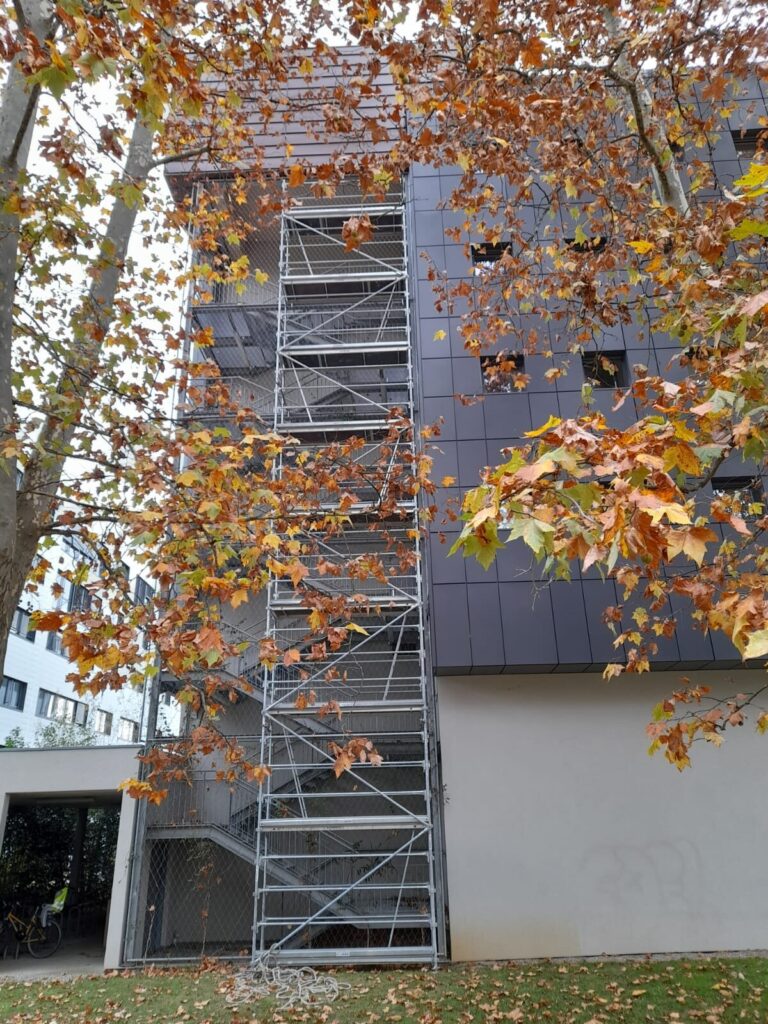 Volées d'escalier et paliers d'une sapine d'accès montée contre la façade, vue depuis le pied de la tour